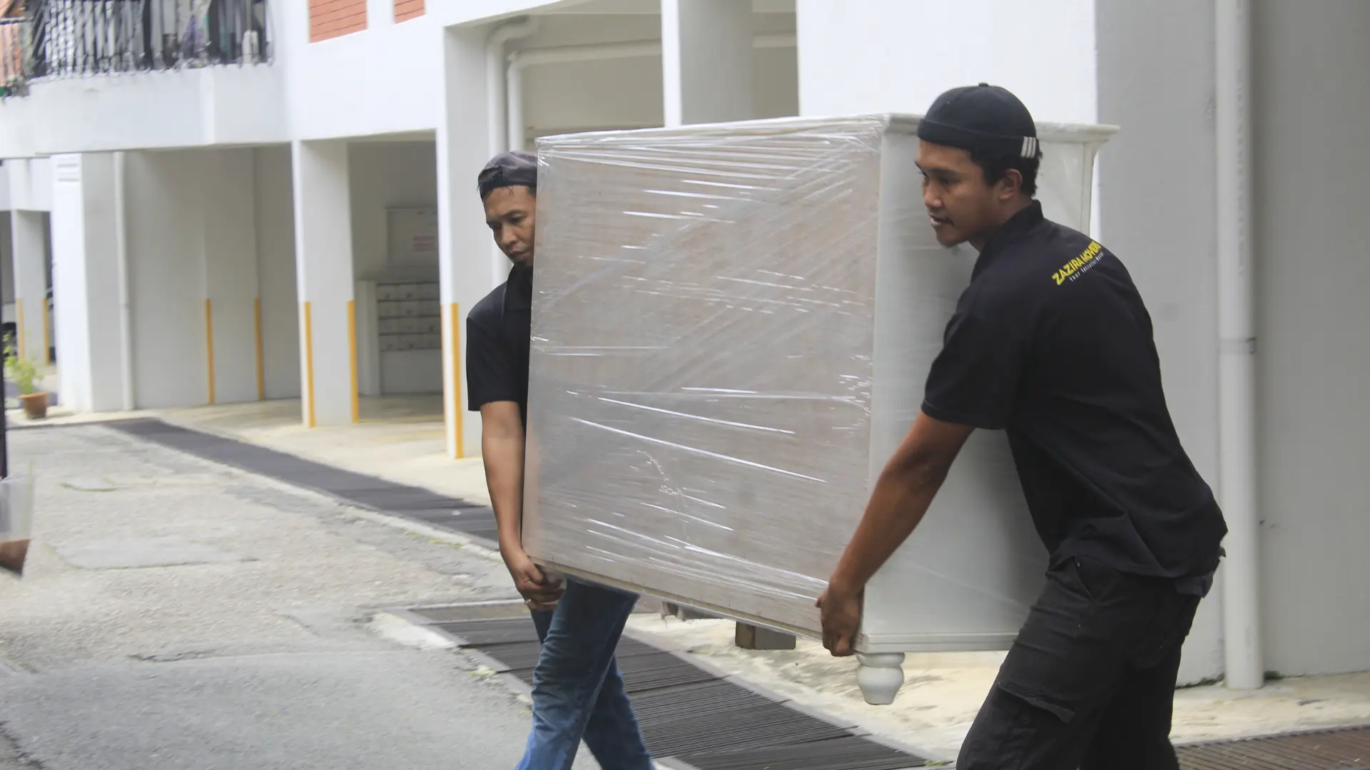 Pricing 5 Professional movers carrying a wrapped cabinet during a residential move
