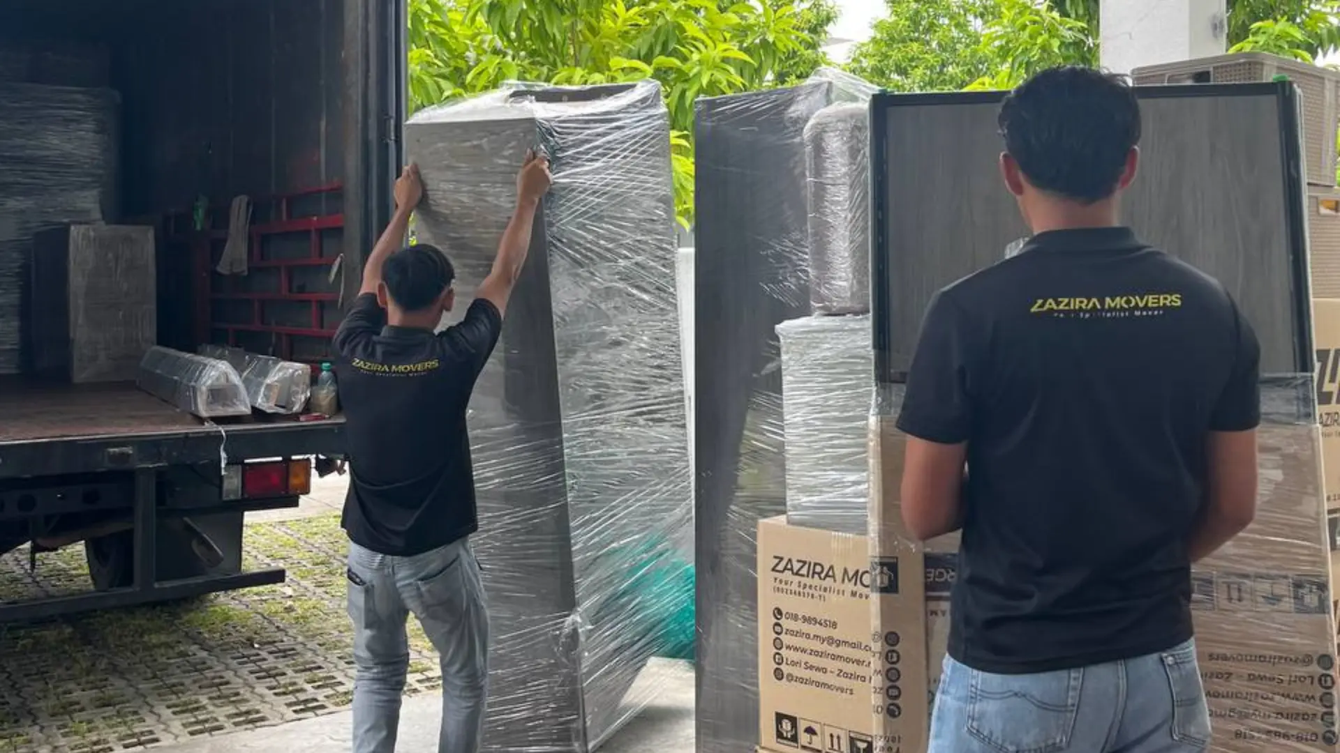 Moving crew loading wrapped furniture into a 1-tonne lorry in Malaysia
