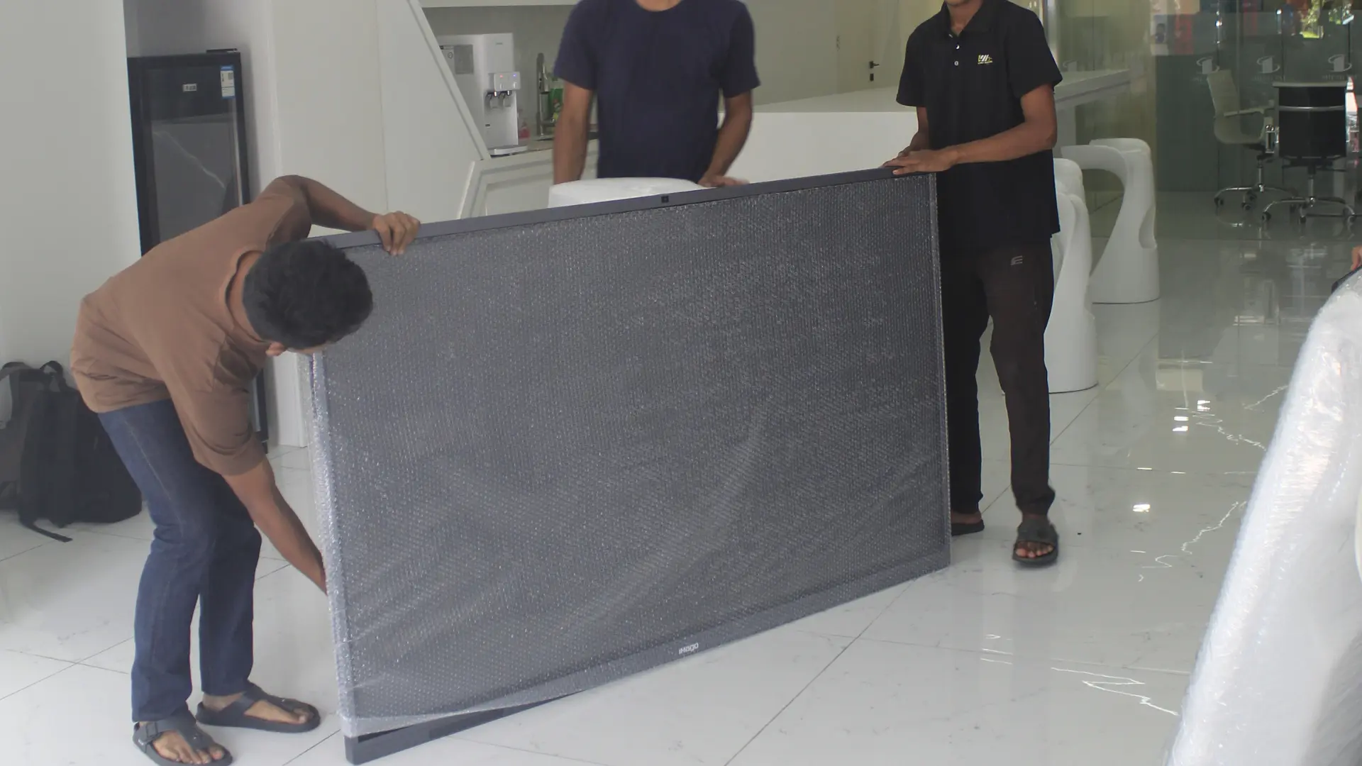 Pricing 6 Zazira Movers team carefully handling and wrapping a large television for relocation